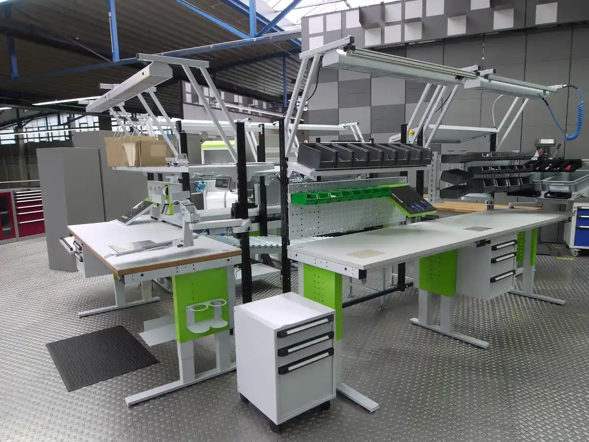 Operator working at a height adjustable workstation with tools positioned within easy reach in a clean manufacturing area.